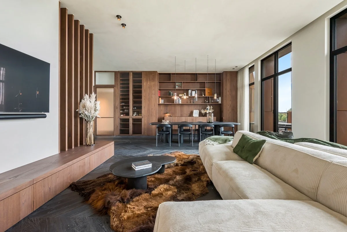 Open living space with a cream sofa, fur rug and dining table behind